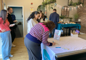 Two ladies filling in their scores on the tea bag pong game, cakes in the background