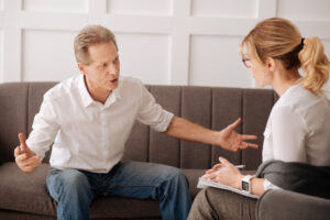 Negative emotions. Emotional angry unhappy man looking at his psychologist and complaining about his problems while looking for advice